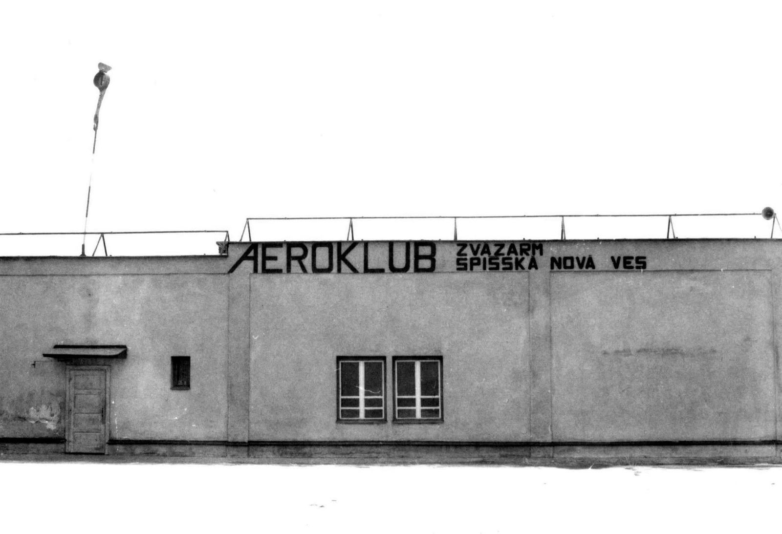 Historická čiernobiela fotografia budovy s nápisom Aeroklub Zväzarm Spišská Nová Ves