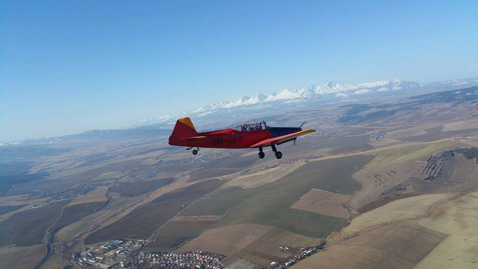 Zlín Z-226 OM-LLY v lete, v pozadí zasnežené Vysoké Tatry