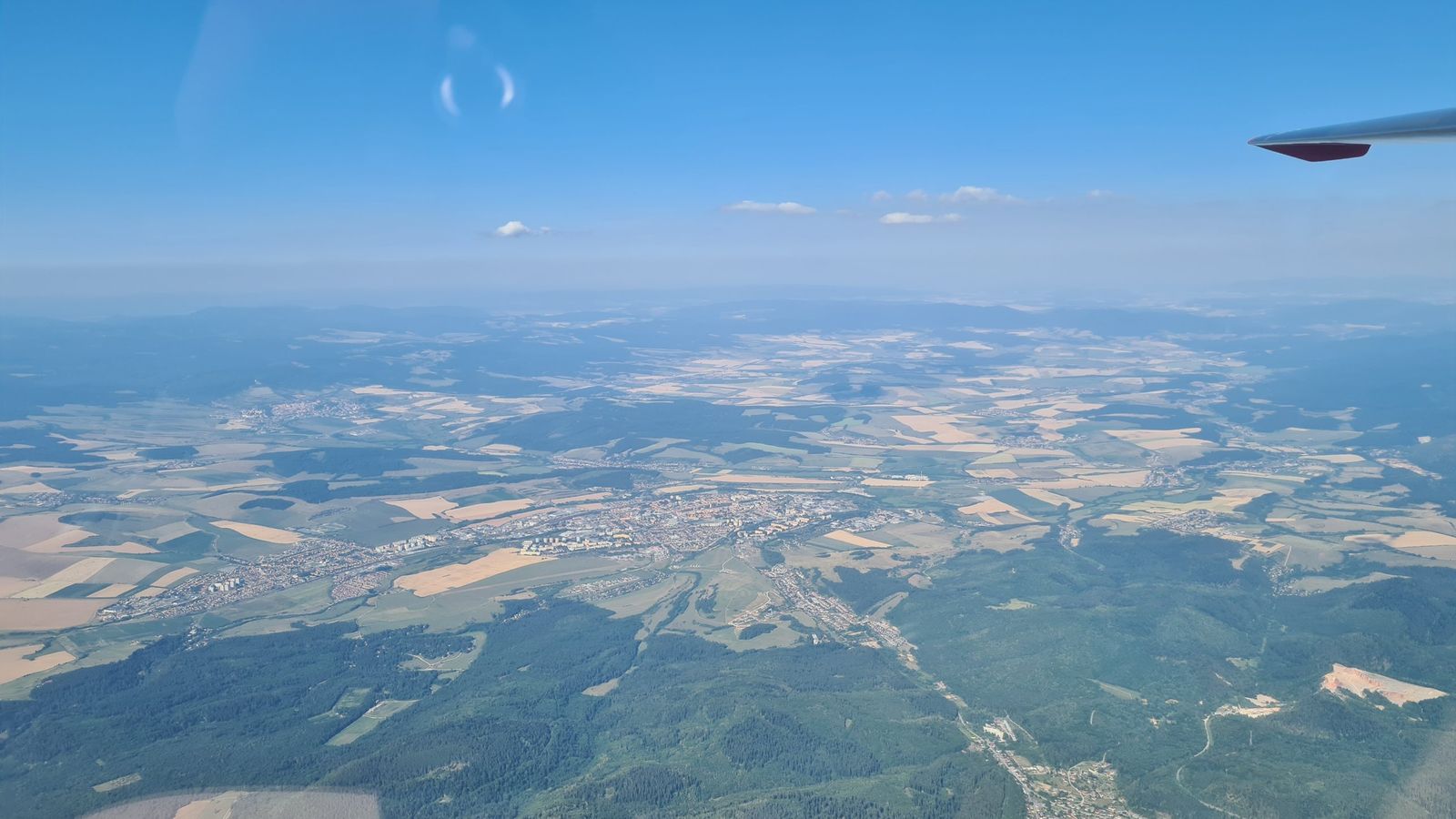 Mesto v kotline medzi poľami a lesmi pri pohľade z výšky