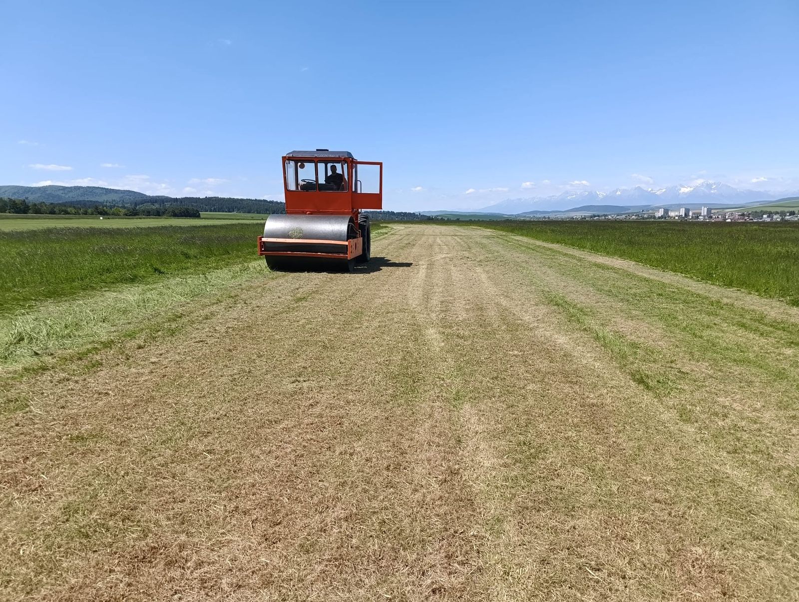 Valcovanie trávnatej dráhy letiska, na obzore Vysoké Tatry